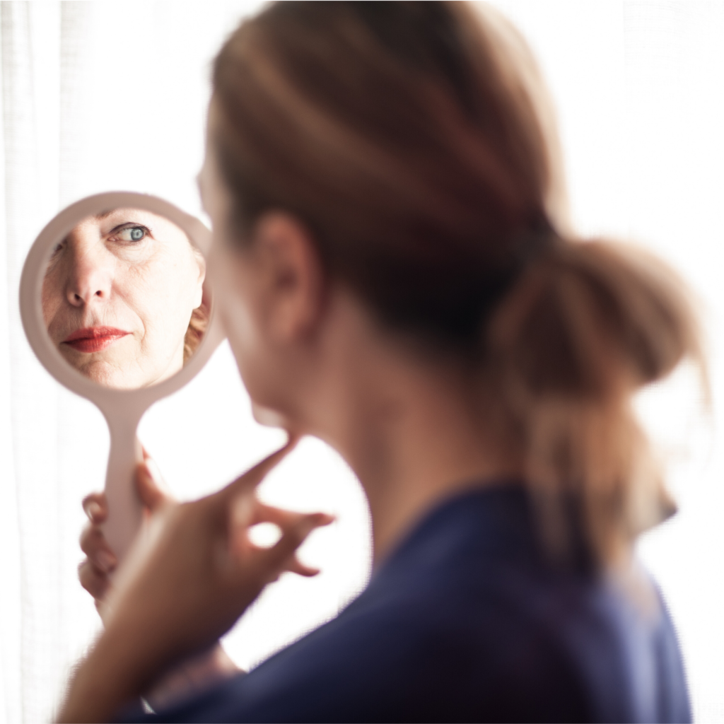 An woman looks at herself in the mirror