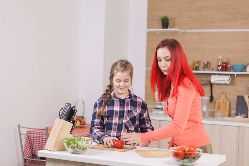 A mother is teaching her daughter to cook